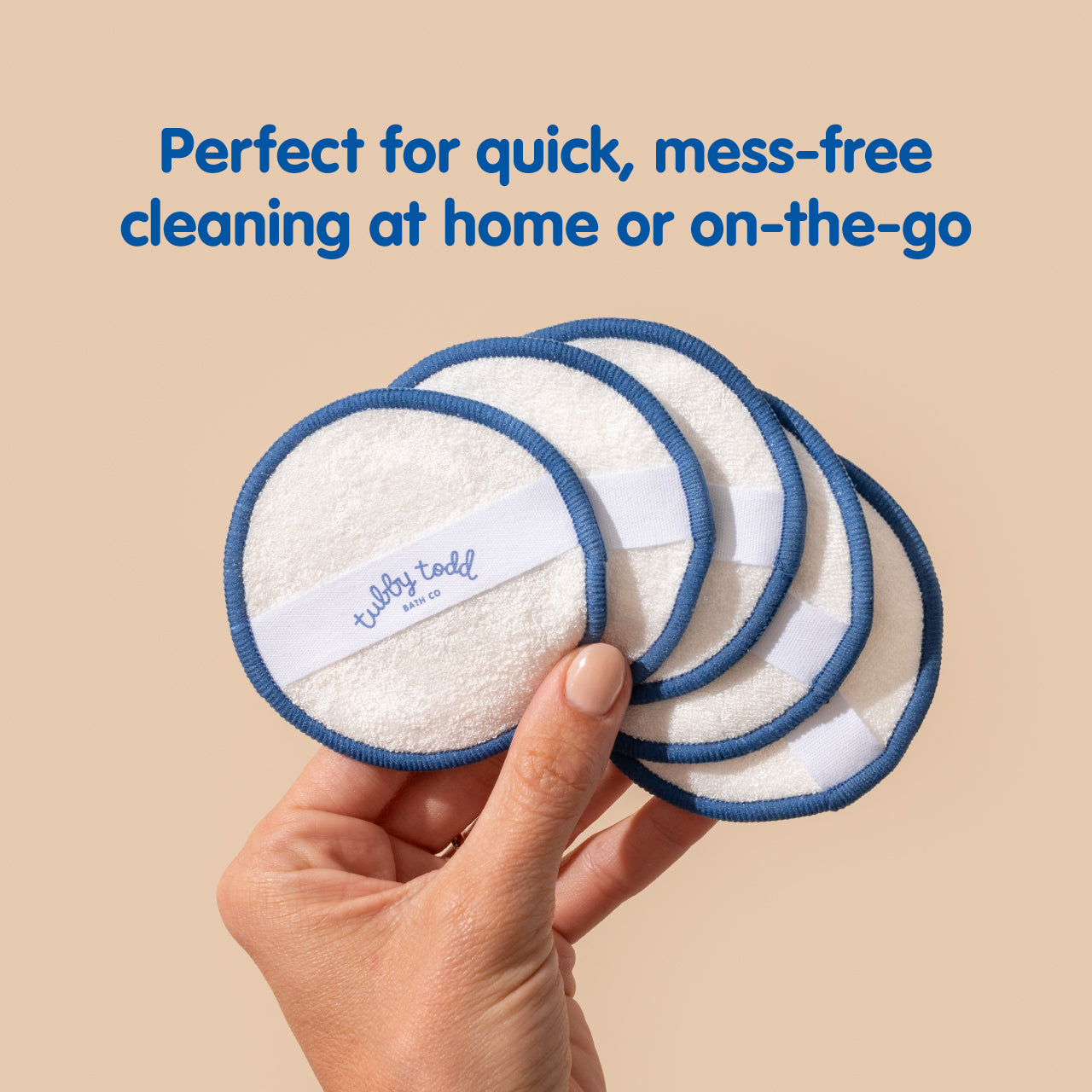Hand holding reusable cleaning pads with blue edges and a beige background
